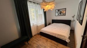 a bedroom with a bed and a window and a chandelier at Sunrise apartment in Bistriţa