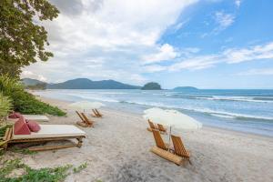 duas cadeiras de praia e guarda-sóis numa praia em Villa Sapê Pousada em Ubatuba