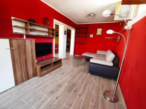 a red living room with a couch and a tv at Apartment Batomalj in Baška