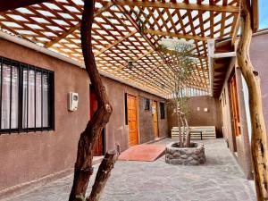 a patio with a wooden pergola and a bench at Hostal Qachi Chentura in San Pedro de Atacama