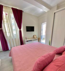 - une chambre avec un lit rose et une télévision dans l'établissement Sea View Apartament, à Mamaia Nord – Năvodari