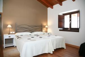 a white bedroom with a bed and a window at Agroturismo La Casa Vieja in Maturana