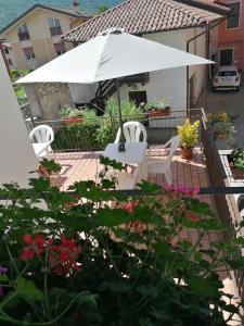 un patio con sombrilla blanca, sillas y flores en B&B RINGAT, en Mori