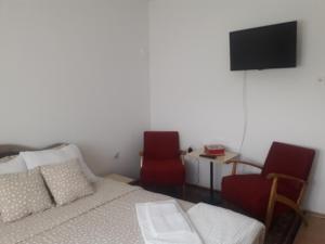 um quarto com uma cama e 2 cadeiras e uma televisão em Kutak- stan na dan em Paraćin