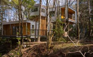 a house in the woods with a wrap around porch at Baumhaus Lodge Schrems in Schrems