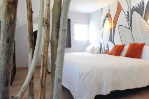 una camera da letto con un letto bianco e cuscini arancioni di Logis Hôtel L'Ayguelade a Bielle