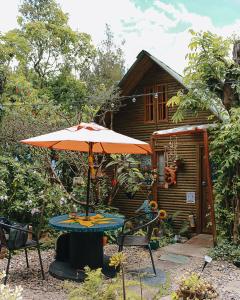 a table with an umbrella in front of a cabin at Cabañas Sinduly Bed & Breakfast in Sopó