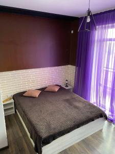 a bedroom with a large bed with purple curtains at lounge apartment in Ivano-Frankivsʼk