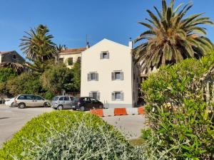a white building in a parking lot with palm trees at Apartment House Bucul in Mali Lošinj