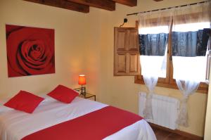 sypialnia z łóżkiem i czerwoną różą na ścianie w obiekcie El Rincón de la Trilla - El Linar w mieście Horcajo de la Sierra