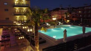 a swimming pool with a palm tree next to a hotel at ASTERAS STUDIOS in Paralia Katerinis