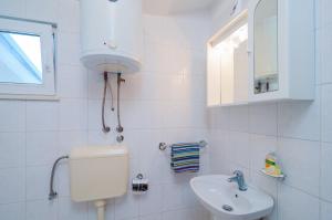 biała łazienka z toaletą i umywalką w obiekcie Apartmani Ban w mieście Poljica