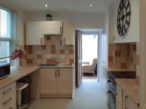 una cocina con armarios blancos y una puerta a un patio en Welcoming 4 Bed Holiday Home in Eastbourne en Eastbourne