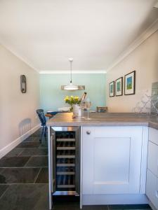 a kitchen with a white island with wine racks at Padstow Escapes - Breakers Holiday Cottage in St Merryn