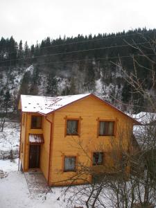 una pequeña casa de madera con nieve en el techo en Sadyba Vyshenka, en Tatariv