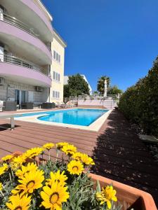 a swimming pool with yellow flowers in front of a building at SKY - beautiful rooftop apartment with shared pool in Split