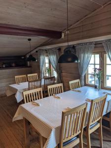 a dining room with two tables and chairs and windows at Neset Skydsstasjon in Flesberg