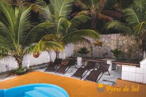 a swimming pool with chaise lounge chairs and palm trees at Pousada Porto do Sol in Nova Viçosa