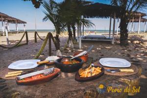 a table with plates of food on the beach at Pousada Porto do Sol in Nova Viçosa