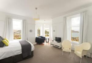 a white bedroom with a bed and a desk and chairs at Greystones B&B in Oban