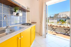 a kitchen with yellow cabinets and a view of a balcony at La Dimora Dei Nonni in Ischia