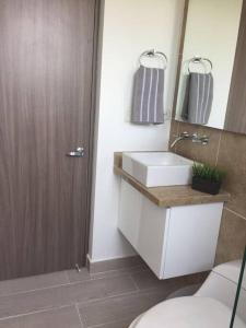 Un baño con lavabo, inodoro y espejo. en Beautiful Beach Apartment in Zazue, en Santa Marta