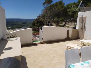 a patio with white walls and tables and chairs at Casina Viestana in Vieste