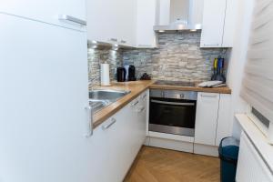 a kitchen with white cabinets and a sink at Schönbrunn Serenity Luxurious Ruby Apartment with Palace Views in Vienna