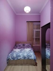 ein lila Schlafzimmer mit einem Bett und einem Fenster in der Unterkunft Siemens House in Tbilisi City