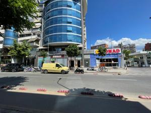 une rue de la ville avec une voiture jaune garée devant un bâtiment dans l'établissement MAK Apartments, à Tirana