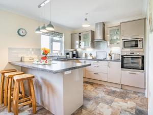 a kitchen with white cabinets and a counter with stools at Yr Hen Ffald in Llanedy