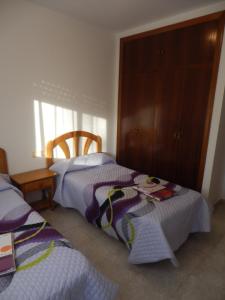 1 dormitorio con 2 camas y armario de madera en Apartamentos Pescadores, en Peñíscola