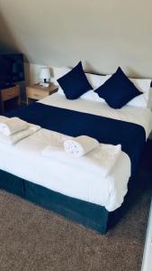 two beds in a hotel room with blue and white pillows at Caithness Inn in Wick