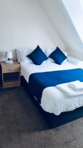 sypialnia z 2 łóżkami z niebieskimi poduszkami i stołem w obiekcie Caithness Inn w mieście Wick