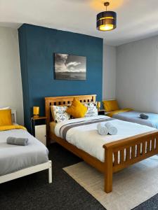 a bedroom with two beds and a blue wall at PolkaDot Winter Gardens - 2 x Large Modern Apartments, Central Blackpool in Blackpool