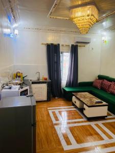 ein Wohnzimmer mit einem grünen Sofa und einer Küche in der Unterkunft Residence SVET in Kribi