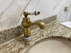 a bathroom sink with a gold water faucet at Flores de Cunha in Cunha +44 photos