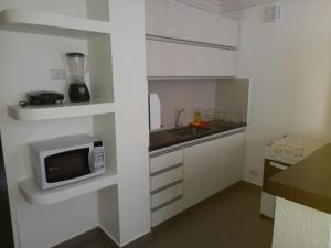 a white kitchen with a microwave and a sink at Apartamento 1011 in Goiânia