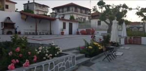 a house with a courtyard with flowers and an umbrella at Olympia studios By Travel Pro Services - Agios Nikolaos Halkidiki in Ayios Nikolaos Sithonia