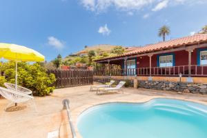 a house with a swimming pool and an umbrella at La Casita. Atardeceres en Puntagorda in Puntagorda