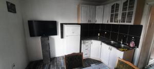 a kitchen with white cabinets and a sink and a tv at Lustica Bay/Radovici in Tivat