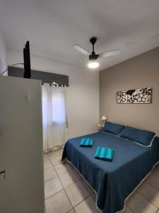 1 dormitorio con 1 cama con almohadas azules y ventilador de techo en Departamentos HF, en Villa María