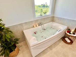 a white bath tub in a bathroom with a window at Elysian Studios in Roda +41 photos