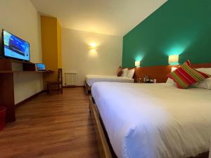 Una habitación de hotel con dos camas y un televisor de pantalla plana. en Usgar San Pedro Boutique, en Cusco