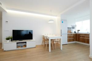 Precioso Loft zona Santiago Bernabéu Madrid في مدريد: غرفة معيشة بيضاء مع طاولة وتلفزيون