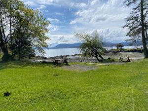 a park with two picnic tables in the grass near the water at Cozy 2 bedroom cabin next to trails and beaches. in Pender Island