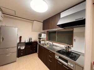 a kitchen with wooden cabinets and a stainless steel refrigerator at Nara Park Blue Sky Private Japanese Traditional House in Nara