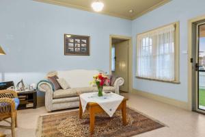 uma sala de estar com um sofá e uma mesa com flores em George Cottage em Sorrento