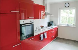 uma cozinha vermelha com um lavatório e armários vermelhos em 2 Bedroom Stunning Home In Rostock-rvershagen em Rövershagen