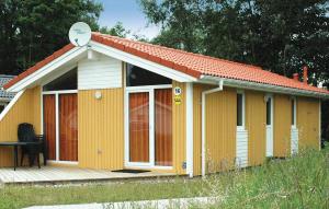 ein kleines gelbes Haus mit einer Veranda und einem Sat-TV in der Unterkunft Schatzkiste 15 - Dorf 4 in Travemünde